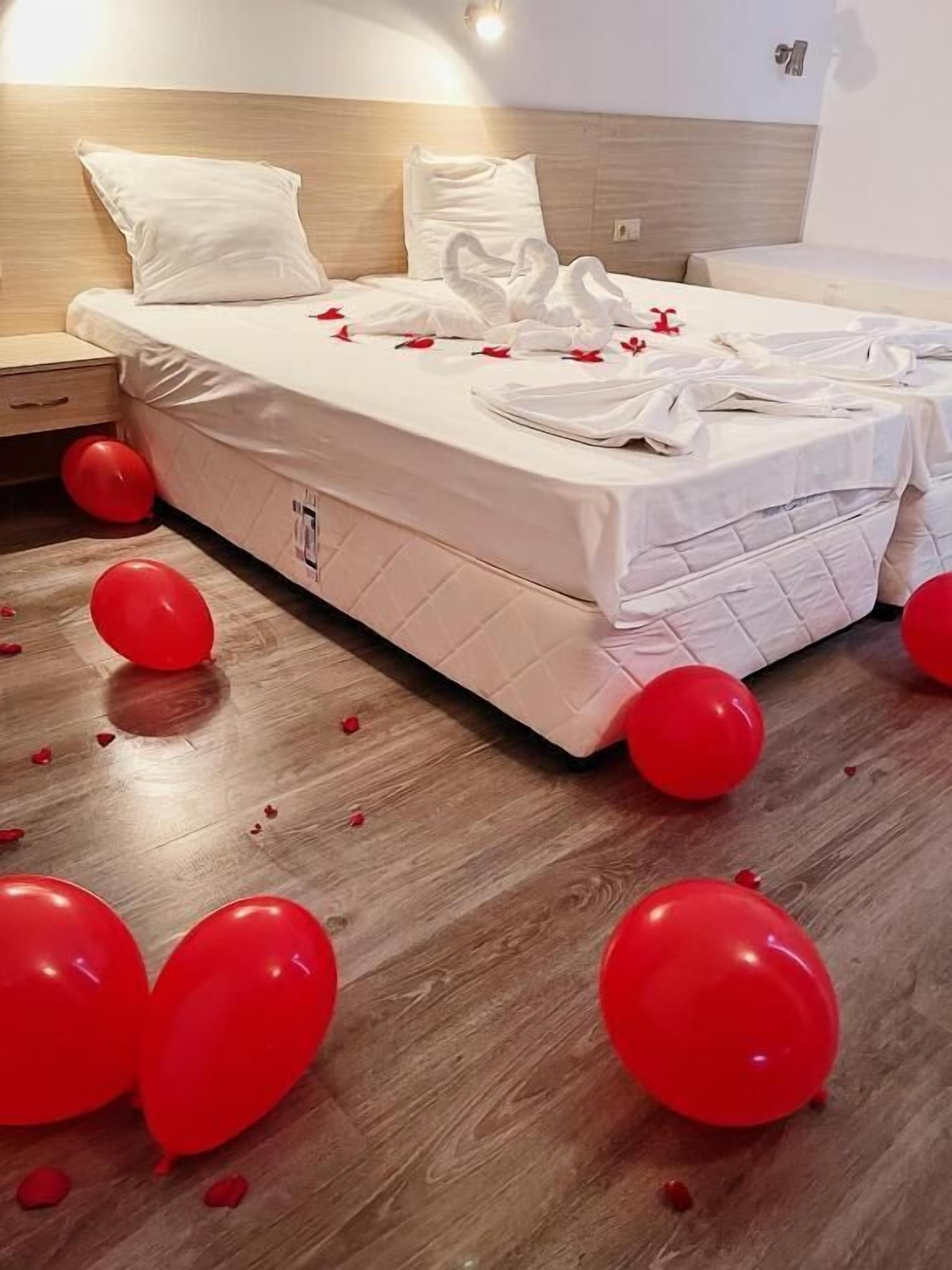A hotel room with a bed, pillows, and a wooden floor.