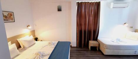 Habitación de hotel con dos camas, una mesita de noche pequeña, aire acondicionado de pared y una cortina.