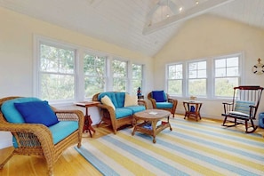 A room with wicker furniture, a striped rug, and large windows. - Cape Beach House with spectacular views and beach access, central AC (Eastham)