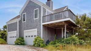 Une maison à deux étages avec un balcon, un garage et une véranda.