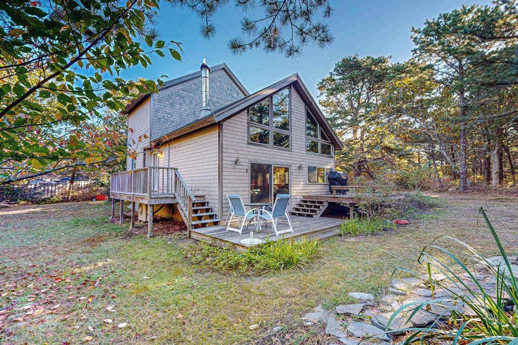 Une maison à deux étages avec une terrasse, une cheminée et un porche équipé de chaises.