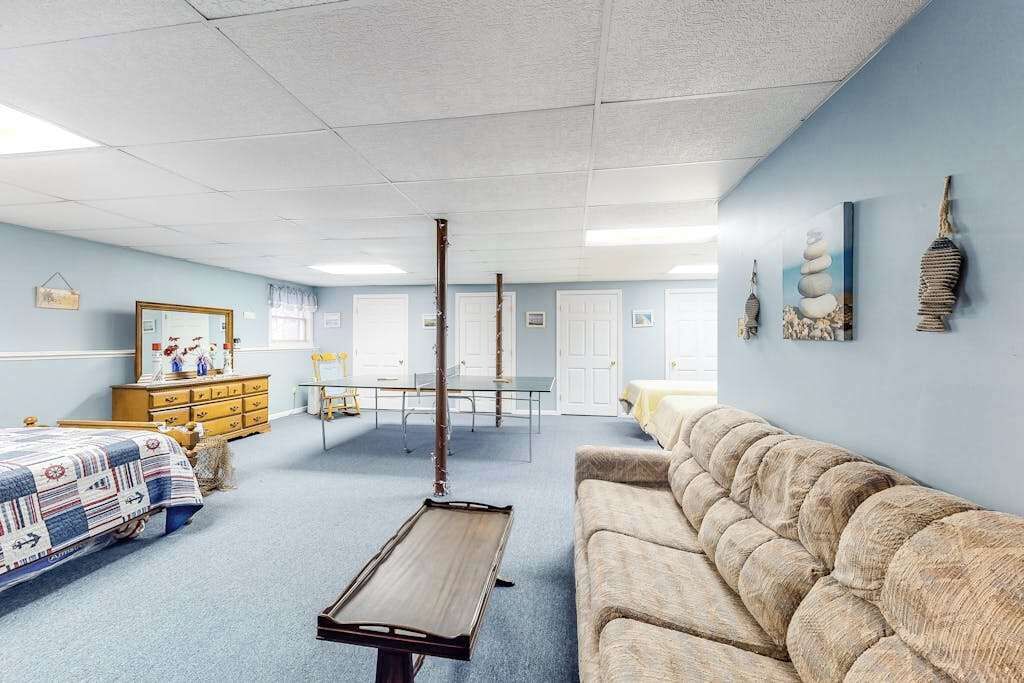 A room with a bed, a sofa, a table, and a wall-mounted shelf.