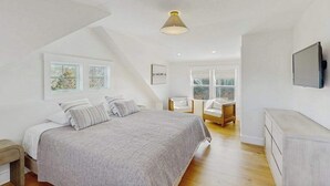 A bedroom with a bed, a chair, a TV, and a window. - Newly built, bayview house steps from the beach with spacious deck, W/D & grill (North Eastham)