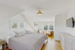 A bedroom with a bed, a chair, a TV, and a window. - Newly built, bayview house steps from the beach with spacious deck, W/D & grill (North Eastham)