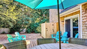 Une terrasse extérieure avec une table et des chaises, une clôture en bois et une maison en arrière-plan.