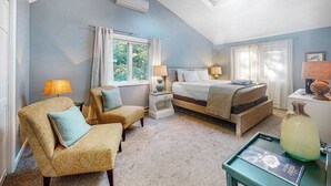 Une chambre à coucher comprenant un lit, deux chaises, une table de chevet, une lampe, une fenêtre et un ventilateur de plafond.
