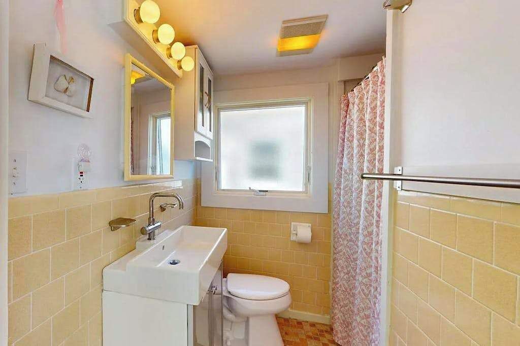 Une salle de bain équipée d’un lavabo, de toilettes, d’un miroir et d’un rideau de douche.