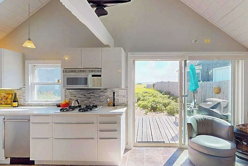 Una cocina moderna con armarios blancos, un microondas integrado y una isla grande con estufa a gas.