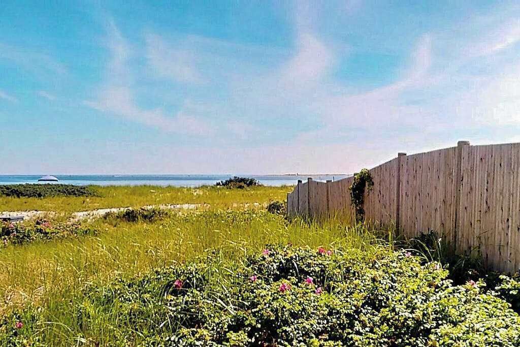 A wooden fence, grassy field, and a body of water.