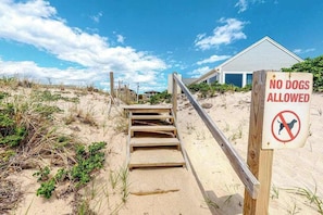 A beach with a wooden staircase leading to a house, and a sign stating 'NO DOGS ALLOWED'. - Newly Renovated Studio with AC, Grill – steps from Private Beach (Truro)