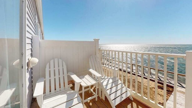 Una terrazza con sedie bianche e vista sull'oceano.