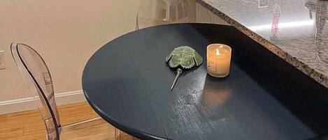 Una mesa redonda con superficie negra, un adorno verde y una vela encendida.