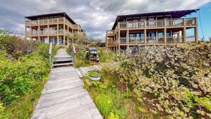 A wooden pathway leading to a building with multiple balconies and a deck area.