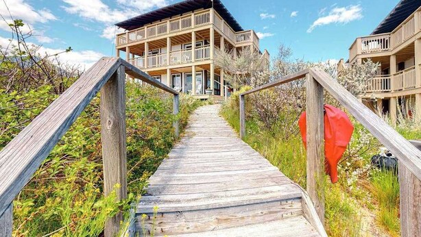 A wooden boardwalk leading to a building with multiple balconies.