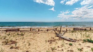 A beach with a wooden fence, a driftwood piece, and the ocean in the background.