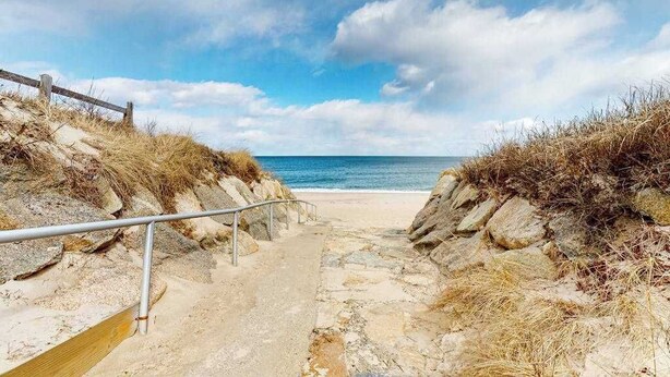 A coastal pathway leading to the beach with a metal railing and a wooden boardwalk. - Duplex home blocks from Manomet Beach with balcony, firepit & outdoor space (Plymouth)