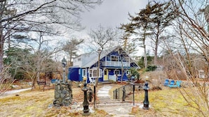 A blue house with a porch, a stone wall, and a pathway leading to the entrance. - Duplex home blocks from Manomet Beach with balcony, firepit & outdoor space (Plymouth)