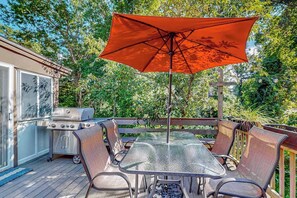 Eine Terrasse mit Grill, Tisch und Stühlen sowie einem Sonnenschirm.