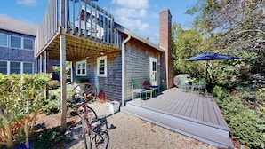 A two-story house with a deck, a bicycle, and a garden. - The Lodge | Condo in Provincetown with harbor views & two decks (Provincetown)