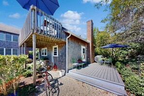 A two-story house with a deck, a bicycle, and a garden. - The Lodge | Condo in Provincetown with harbor views & two decks (Provincetown)