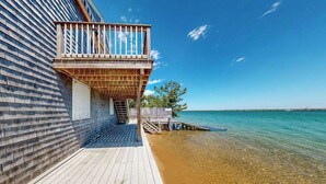 Een houten terras leidt naar een balkon met uitzicht op het strand.