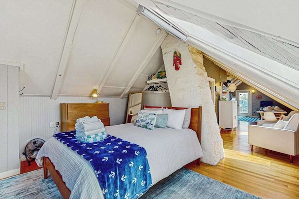 A bedroom with a bed, a wooden headboard, a fan, and a view of a dining area.