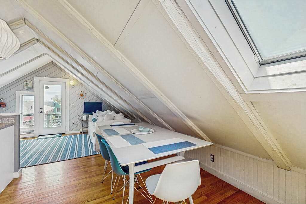 Un comedor con mesa y sillas, vistas al exterior y una puerta que da a otra habitación.