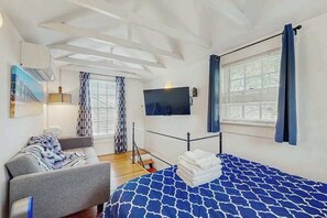 A bedroom with a bed, a sofa, a TV, and a window with curtains. - Charming condo with shared courtyard - walk to the beach and dining (Provincetown)