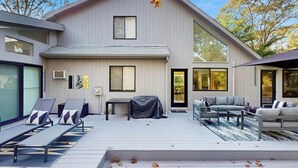 Et moderne hus med en overdækket terrasse, udendørs møbler og store vinduer.