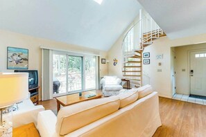 A living room with a sofa, a TV, a staircase, and a door.
