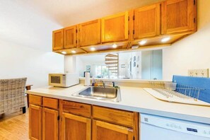 A kitchen with wooden cabinets, a microwave, a sink, and a dishwasher.