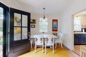 A dining area with a black door, white chairs, a table, and a hanging light fixture. - Beautiful, cozy ranch home w/ a deck - walking distance to Downtown Chatham (Chatham)