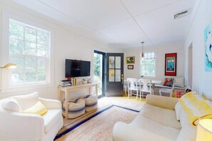 A living room with white furniture, a TV, and a door leading to another room. - Beautiful, cozy ranch home w/ a deck - walking distance to Downtown Chatham (Chatham)