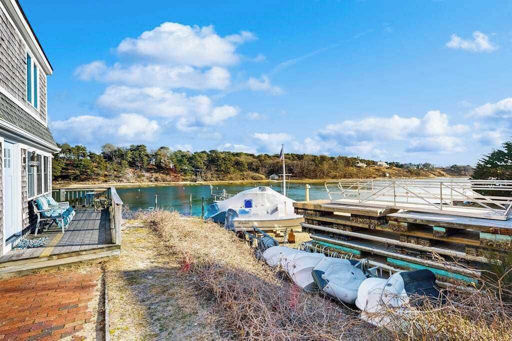 Een pand aan het water met een steiger, een boot en terras.