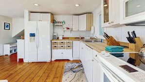 Een moderne keuken met witte kastjes, een inbouwoven en een houten aanrecht.