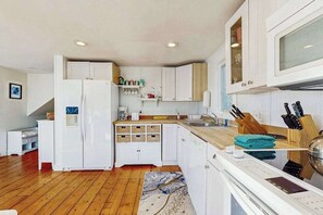 Una cocina moderna con armarios blancos, horno empotrado y encimera de madera.