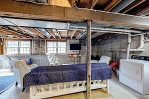 Een kamer met een bed, een stoel, een wasmachine en een televisie.