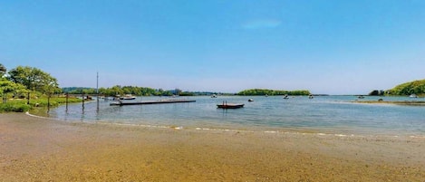 A beach with clear water, boats, and a dock.