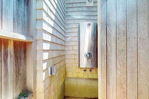 A small, enclosed bathroom with a shower, a toilet, and a sink. - Coastal home with screened porch, W/D, & amazing location (Centerville)