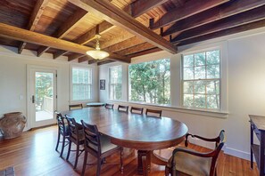 A large wooden dining table surrounded by chairs in a room with high ceilings and large windows. - Coastal home with screened porch, W/D, & amazing location (Centerville)