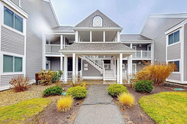 A two-story building with a central entrance, a covered porch, and a staircase leading to the upper level.
