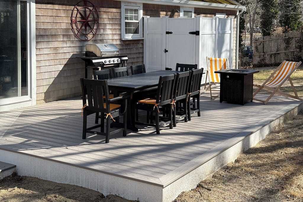 Une terrasse avec un barbecue, une table et des chaises.