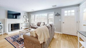 A living room with a fireplace, a sofa, a coffee table, and a TV. - Beautifully renovated home near Scargo Lake with deck, W/D, AC, games, & yard (Dennis)