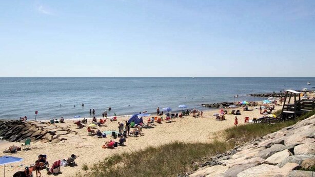 En strand med mennesker, telte og en redningsplatform.