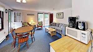 En stue med spisebord, stole, sofa, kaffemaskine og mikrobølgeovn.
