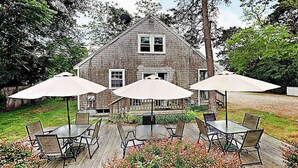 Et hus med terrasse, udendørs møbler og en parabol.