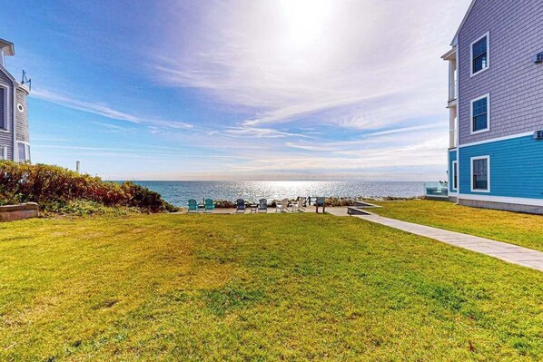 A residential property with a grassy yard, a pathway, and a view of the sea.
