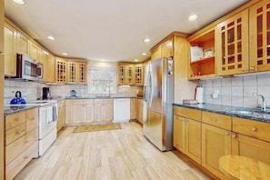 A modern kitchen with wooden cabinets, stainless steel appliances, and a tiled backsplash.