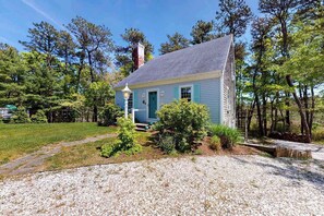 A small house with a sloped roof, a chimney, and a front porch. - Waterfront escape with gas grill, furnished deck, fast WiFi, beach access nearby (Dennis Port)