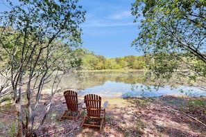 Two Adirondack chairs by a calm lake surrounded by trees. - Pond view home w/ AC, sunroom, kayak & near town and beaches (Dennis)